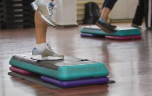 Image of legs doing step aerobics indoors.